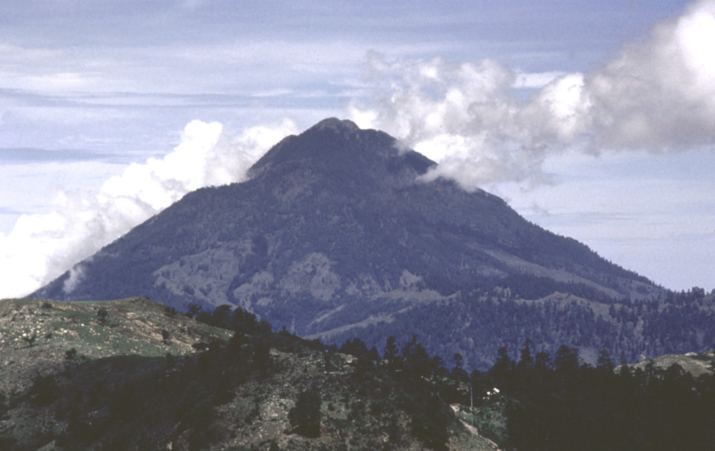 Tacaná is located on the México/Guatemala border at the far NW end of the Central American volcanic belt. It is seen here from the Guatemalan side of the border to the ENE, where it rises steeply above a 9-km-wide caldera surrounded by deeply eroded plutonic rocks. Historical activity has included mild phreatic eruptions, but stronger explosive activity and production of pyroclastic flows occurred earlier. Photo by Bill Rose, 1986 (Michigan Technological University).