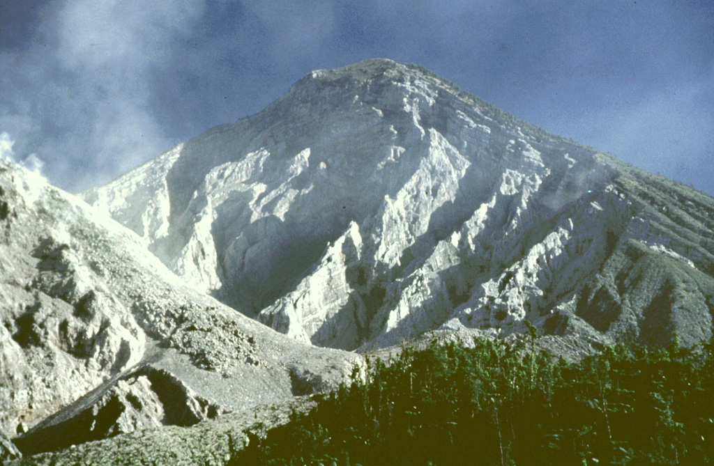 The eroded headwall of the 1.5-km-wide 1902 crater extends from just below the summit down to 2.2 km elevation, where a volume of 0.5 km3 was removed during the eruption. The Santiaguito lava dome complex (left) began growing in the new crater in 1922. This 1991 view shows a lava flow descending the right flank of the dome. Photo by Bill Rose, 1991 (Michigan Technological University).