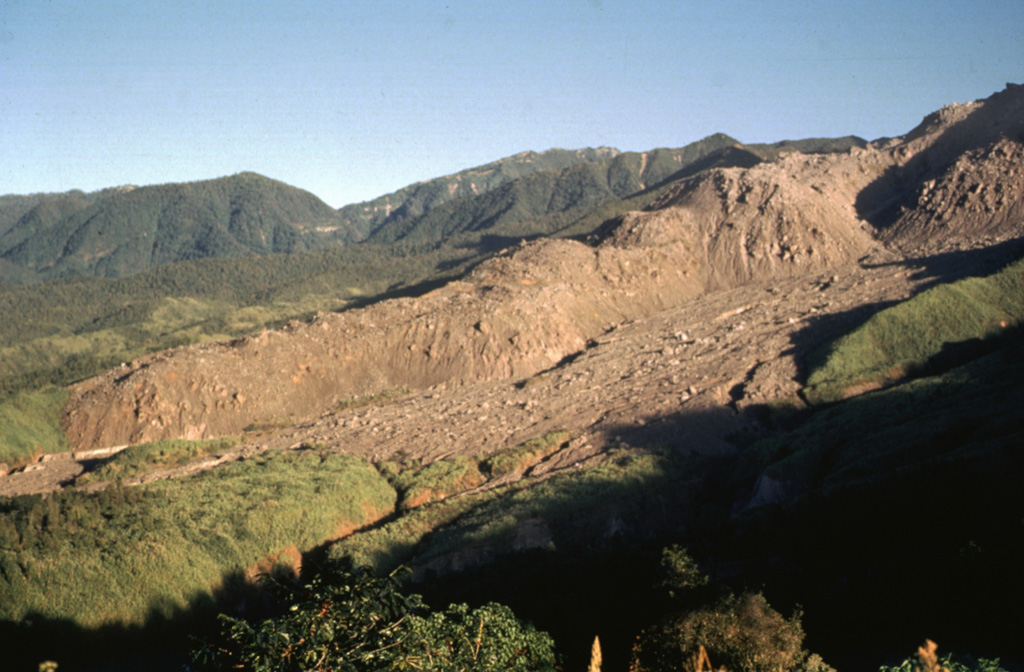 The thick unvegetated lava flow descending diagonally across the photo originated from El Brujo (upper right) at the western end of the Santiaguito lava dome complex. This north-looking 1970 view shows Santiaguito's SW-flank topography prior to a period of rapid lava extrusion from El Brujo during 1972-75. The flanks of Siete Orejas volcano form the horizon. Photo by Bill Rose, 1970 (Michigan Technological University).