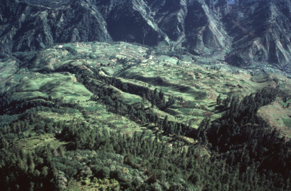 An aerial view of the Río Las Majadas valley in Guatemala on the NNE side of Tacaná volcano shows thick deposits of lahars and debris avalanches filling the valley. These deposits provide a flat surface for agricultural use in deeply eroded terrain. The valley drains from its headwaters in Guatemala through México into the Pacific Ocean, and lahars during future eruptions could affect both countries. Photo by Bill Rose, 1986 (Michigan Technological University).