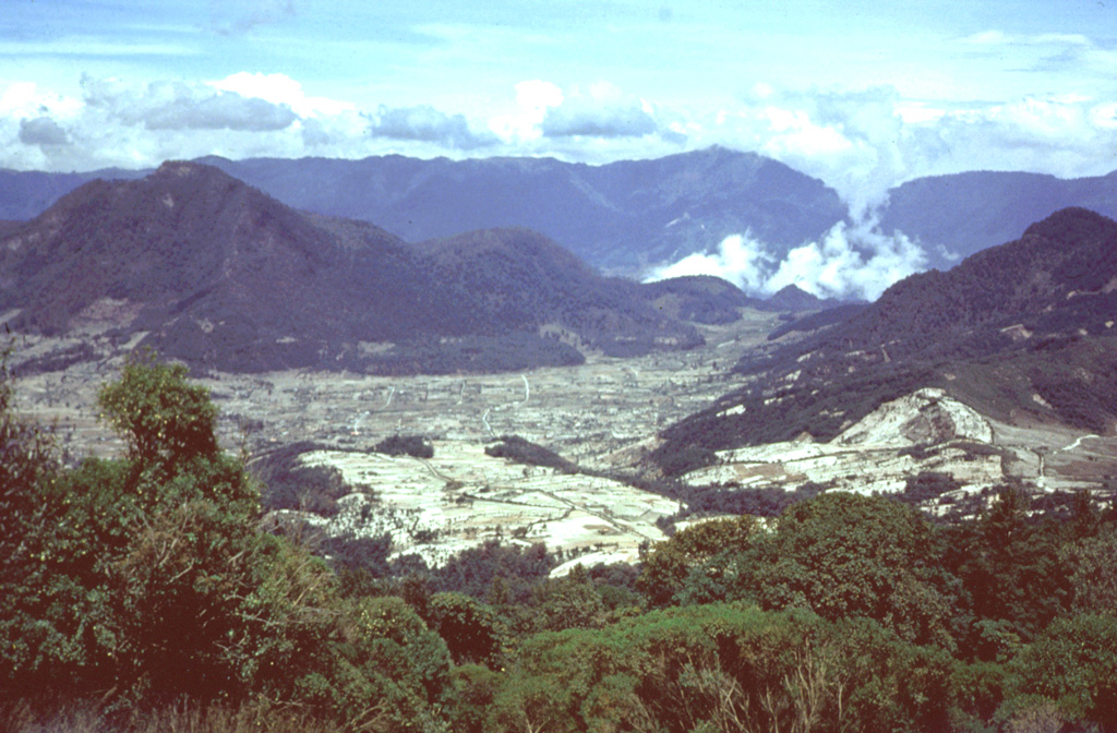 The Cerro Quemado lava dome (left), seen here from Siete Orejas volcano, is one of a series of lava domes along the margin of the Almolonga caldera. The  Cerro Quemado dome complex formed during the Holocene from eruptions along at least eight vents. One of these domes forms the low rounded feature below the center horizon. Santa María lies just out of view to the right, and the western side of the Santo Tomás volcanic complex forms the horizon. Photo by Bill Rose, 1975 (Michigan Technological University).