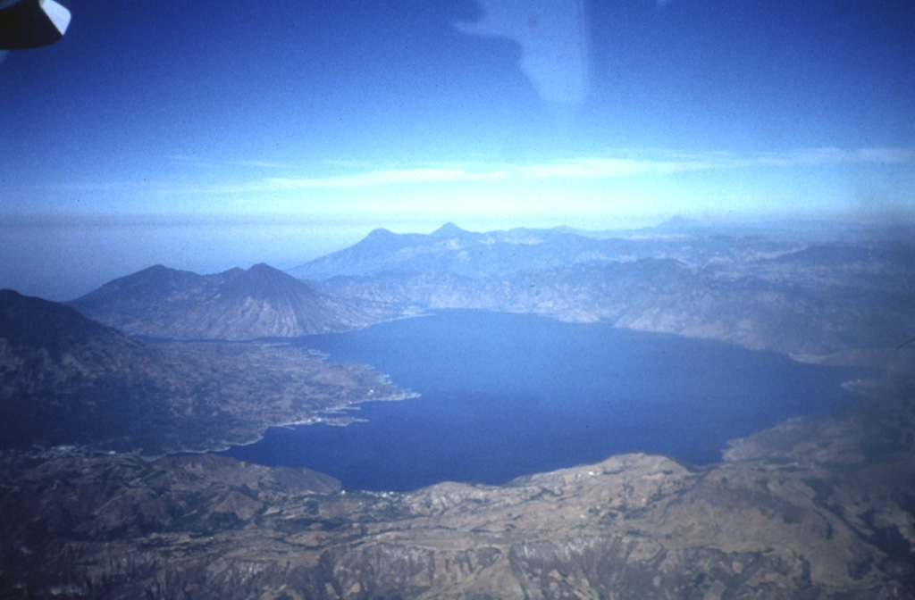 A panoramic view to the west across Lake Atitlán shows the flanks of Tolimán volcano extending to the lakeshore on the left, San Pedro volcano at the SW end of the lake, and the two peaks of Santo Tomás (left) and Santa María (right) on the center horizon. Tajumulco volcano appears in the distance at the upper right. Lake Atitlán occupies the northern half of the youngest Atitlán caldera, which formed during the eruption of the Los Chocoyos Ash about 84,000 years ago. Photo by Bill Rose, 1972 (Michigan Technological University).