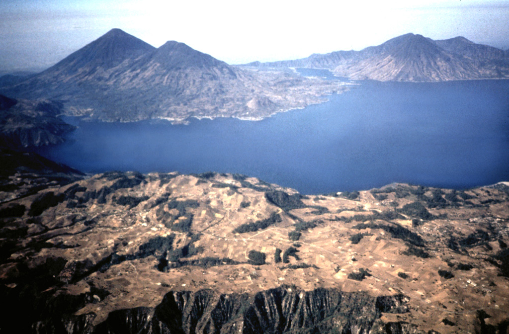 Three stratovolcanoes fill the southern half of Atitlán caldera in this view from the NE. Atitlán caldera formed during three major explosive eruptions from the Miocene to late Pleistocene. Atitlán volcano (far left) was constructed above the southern rim of the youngest caldera, Atitlán III, whose low southern rim is visible on the center horizon beyond narrow Santiago bay. Tolimán (right of Atitlán) and San Pedro (far right) overlie the rim of Atitlán II. The buried rim of Atitlán I lies below the shoreline of Tolimán. Photo by Bill Rose, 1980 (Michigan Technological University).