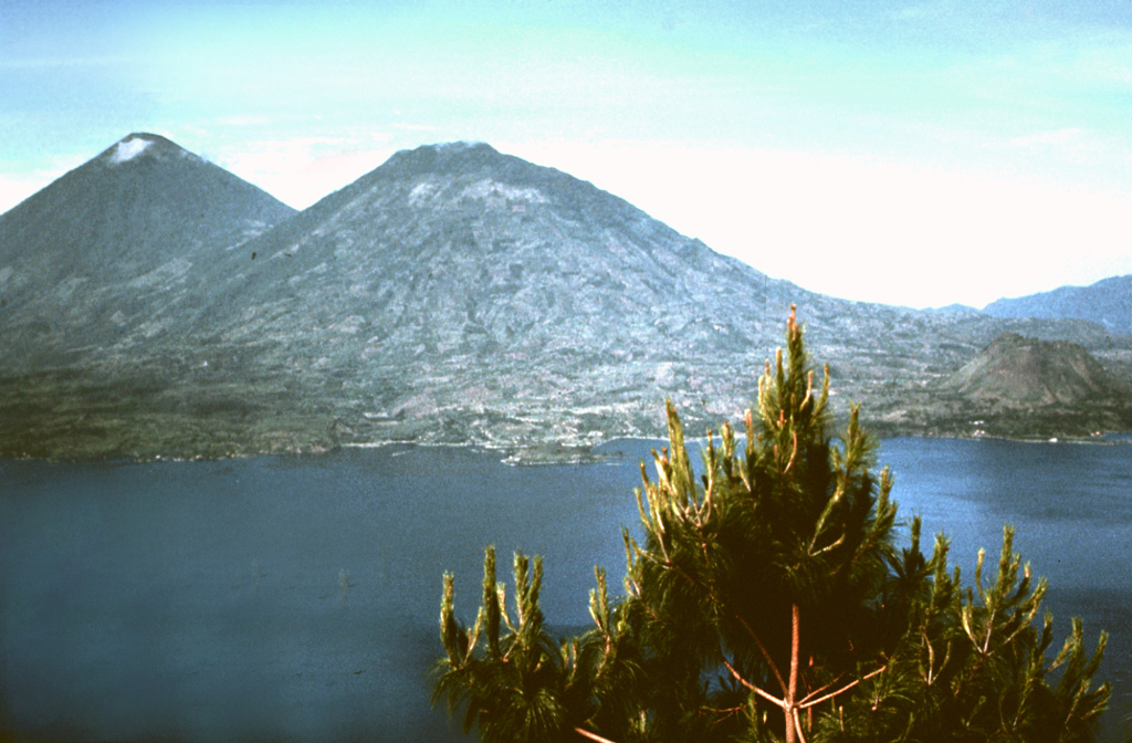 Volcán Tolimán (center) towers above the south shore of scenic Lake Atitlán. Tolimán and the adjacent Atitlán (upper left) were constructed within the Pleistocene Atitlán III caldera, near its inferred southern margin. In contrast to the tephra-covered surface of Volcán Atitlán, the surface of Tolimán is dominated by thick lava flows. The recent eruptions of Tolimán were primarily effusive eruptions from flank vents. The resulting lava flows extend into the lake and produce the irregular shoreline. Photo by Bill Rose, 1972 (Michigan Technological University).