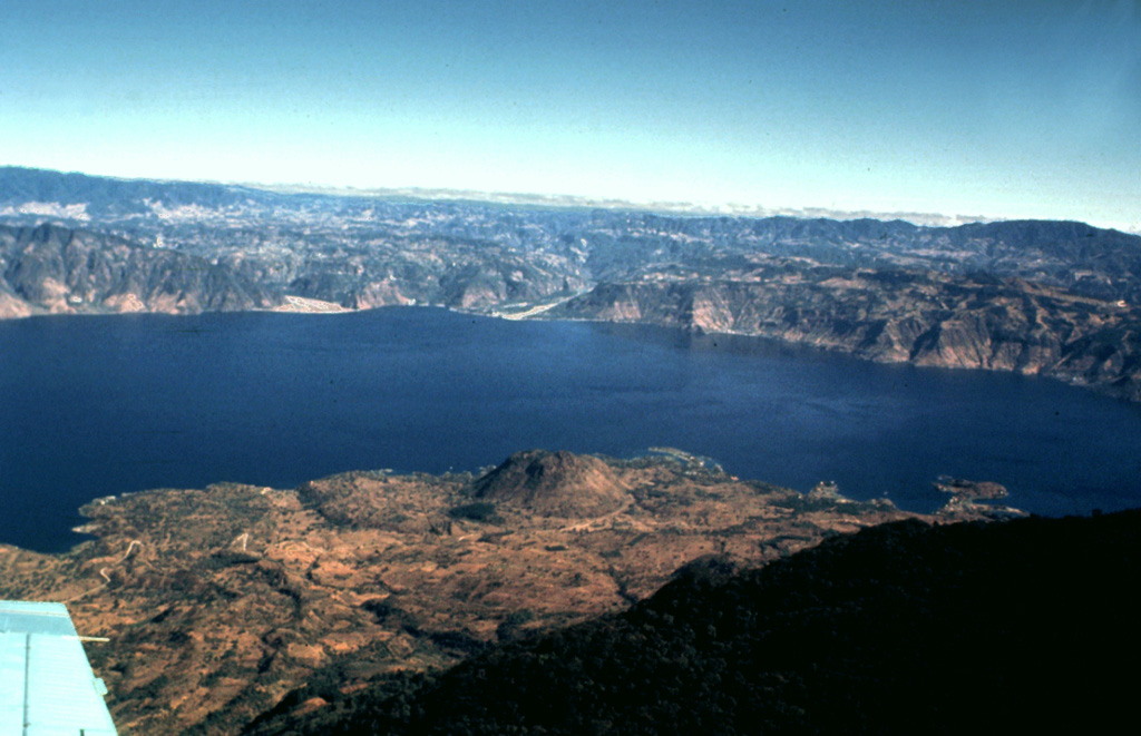 Lake Atitlán fills the northern half of the Atitlán III caldera, which formed about 84,000 years ago following eruption of the Los Chocoyos Ash. The 18-km-long caldera lake is seen here from the south, with the flanks of the post-caldera Tolimán volcano in the foreground. The relatively flat lake floor is 300 m below the water surface, and caldera walls rise to about 1 km above the lake.  Photo by Bill Rose, 1980 (Michigan Technological University).