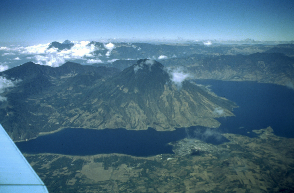 Volcán San Pedro (center) occupies the SW corner of  the roughly 85,000-year-old Atitlán III caldera.  San Pedro is seen here across narrow Santiago Bay from the lower slopes of Atitlán and Tolimán volcanoes.  The 3020-m-high San Pedro has a shallow summit crater that is breached to the NW.  The age of the most recent activity of San Pedro is unknown, although the volcano is more vegetated and erosionally modified than the twin volcanoes of Tolimán and Atitlán and is clearly the oldest of the three post-caldera volcanoes. Photo by Bill Rose, 1980 (Michigan Technological University).