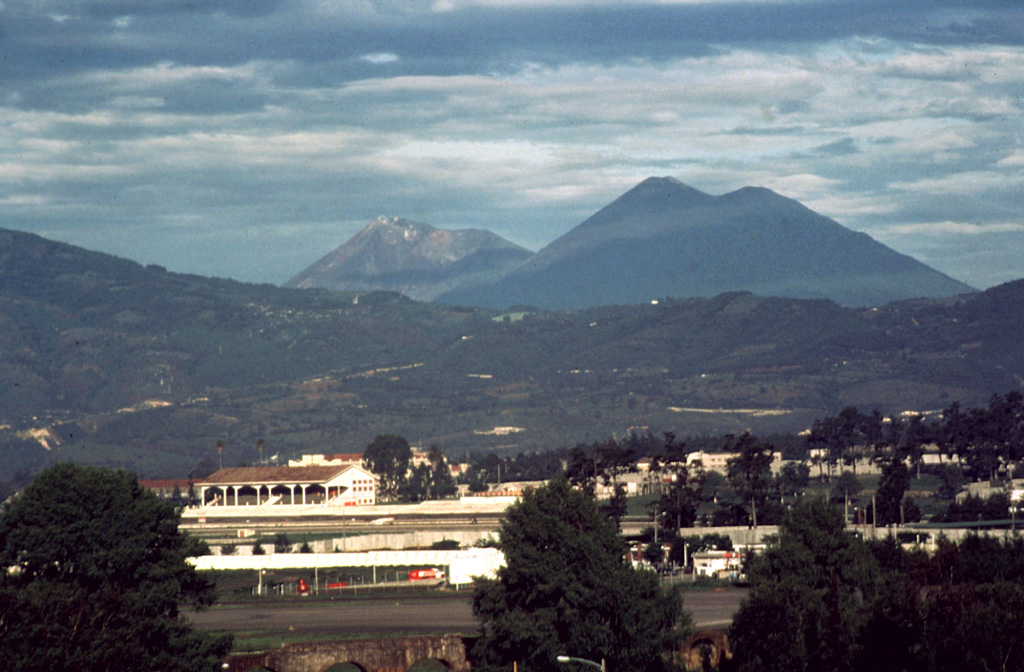 Acatenango (right) is seen here with Fuego at the center in 1986. Volcán Acatenango was constructed during three eruptive periods post-dating the roughly 84,000-year-old Los Chocoyos Ash from Atitlán caldera. The eruptive period of Yepocapa, the northern peak of Acatenango, ceased about 20,000 years ago. The eruption of the southern and highest cone, Pico Mayor began at that time. Photo by Bill Rose, 1986 (Michigan Technological University).