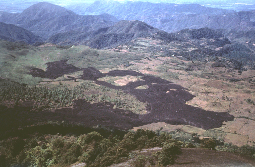 In February 1972 a lava flow from vents at the base of MacKenney cone at Pacaya descended the western flanks and covered farmlands on the caldera floor. The flow was diverted around topographic irregularities, forming several large kipukas. Lava effusion began on 2 February and lasted until the 27th. This December 1972 photo was taken from the summit of MacKenney cone with a village to the upper right  Photo by Bill Rose, 1972 (Michigan Technological University).