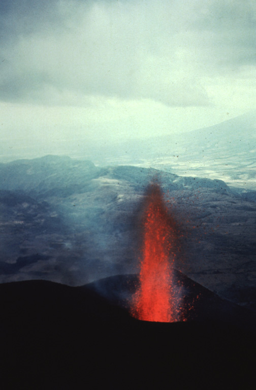 Incandescent lava rises from MacKenney crater early in the 1965-89 Pacaya eruption. The date of the photo is not certain but may have been around 1967. This view looks west from the summit of MacKenney cone with the flank of Volcán de Agua in the distance. Photo by Alfredo MacKenney (courtesy of Bill Rose, Michigan Technological University).