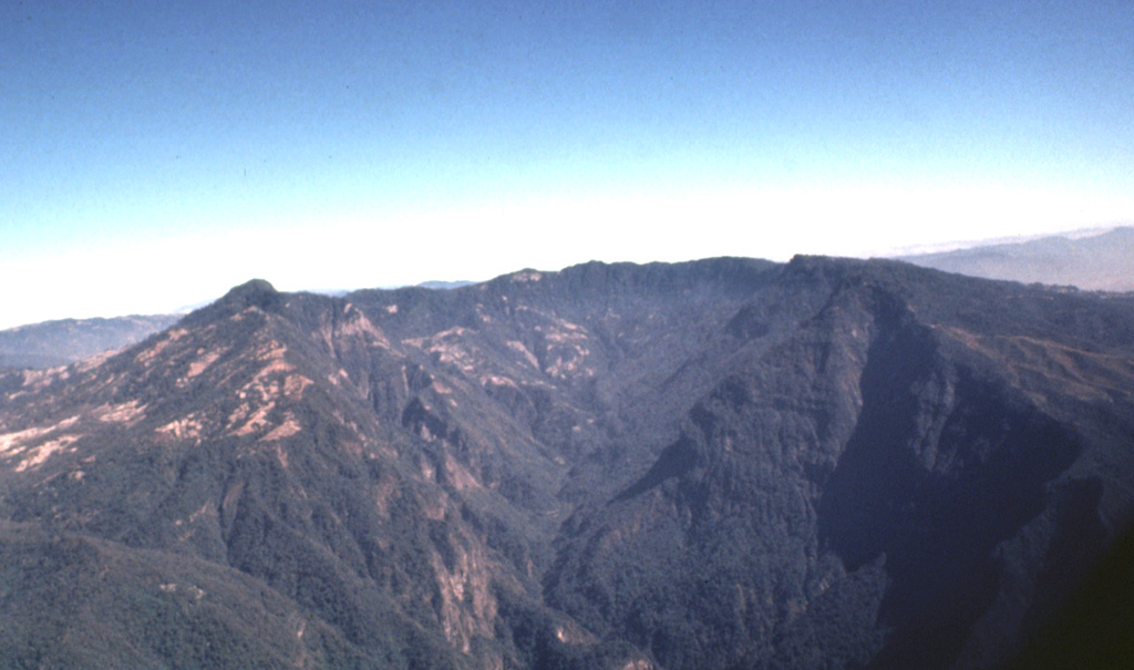 The massive breached caldera of Siete Orejas volcano is seen here from the south, the direction in which it is breached by the Ocosito river.  Irregularities on the broad rim of the 3.5 x 10 km caldera give the volcano its name, which means "Seven Ears."   Photo by Bill Rose, 1980 (Michigan Technological University).