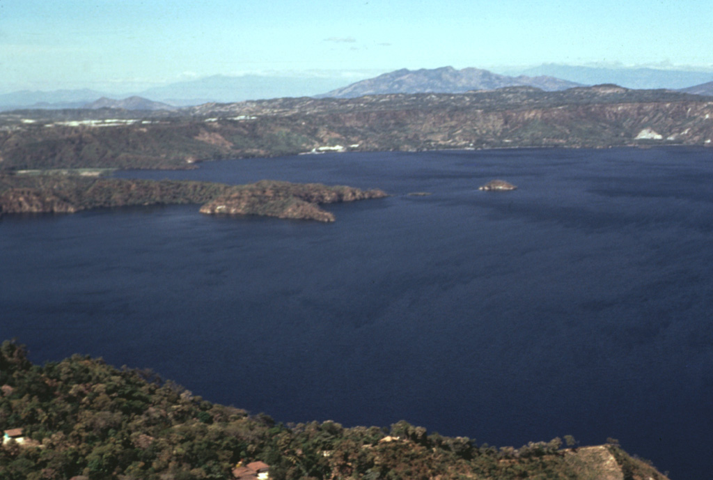 The western side of Lake Ilopango is seen from the southern rim of Ilopango caldera. The broad peak on the right-hand horizon is the Pleistocene Guazapa volcano. The northern wall of Ilopango caldera rises about 400-500 m above the lake. Much of the caldera rim contains thick caldera-forming eruption deposits, and some lava domes are exposed in the caldera wall. Photo by Bill Rose, 1978 (Michigan Technological University).