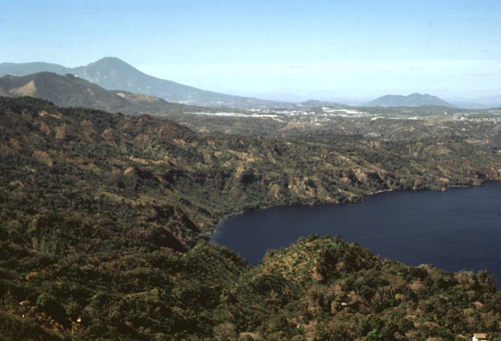 The SW corner of Ilopango caldera is visible in the foreground with the outskirts of the capital city of San Salvador behind it. The high peak on the left horizon (NW) is El Picacho, part of the San Salvador volcanic complex, a recently active volcano overlooking the capital city. Below it to the left is San Jacinto, a Pliocene lava dome complex. The broad peak in the background to the right is the Pliocene Cerro Nejapa volcano. Photo by Bill Rose, 1978 (Michigan Technological University).