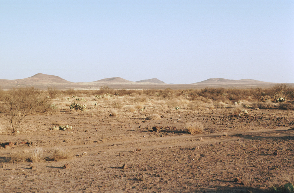 A cluster of cinder cones of the Camargo volcanic field lies within the arid northern Bolsón de Mapimí graben in north-central México, about 150 km SW of Big Bend National Park in Texas.  More than 300 volcanic vents, mostly cinder cones and lava cones, are located in a broad 2500 km2 lava plateau that extends 60 km E-W and 70 km N-S.  The Camargo field is mostly Pliocene in age, but activity continued into the Pleistocene. Photo by Jim Luhr, 1996 (Smithsonian Institution).