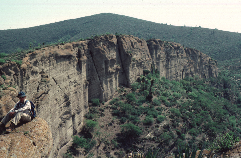 A thick sequence of bedded pyroclastic-surge deposits is exposed in the vertical western wall of La Joya Prieta maar in the Santo Domingo volcanic field in the southern Basin and Range province in the state of San Luis Potosí.  The Santo Domingo field contains a group of four maars, the largest of which is the 750 x 1000 m wide La Joya de los Contreras maar, along with several alkalic cinder cones and associated lava flows.  The Santo Domingo maars are the source of mantle-derived spinel-lherzolite xenoliths and deep-crustal granulite xenoliths. Photo by Jim Luhr, 1987 (Smithsonian Institution).