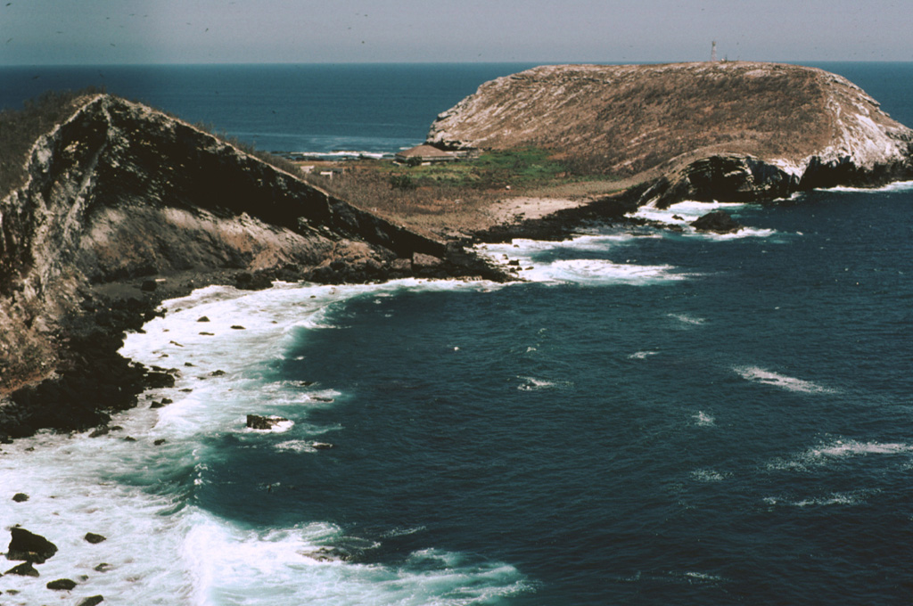 The flat-topped Cerro El Faro cone (upper right) lies across a low isthmus at the southernmost tip of Isla Isabel. It is seen here across the Acantilado Mayor Bay from Cerro del Mirador, the high point of the small 1.5-km-long island. Wave erosion has eroded the flank of Monte Transverso to the left. The two cones are connected by a lava flow. Photo by Jim Luhr, 1999 (Smithsonian Institution).