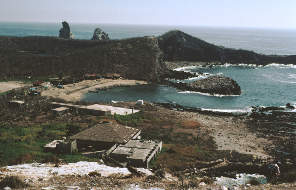 A biological research station and fishermen's shacks line the shores of Playa Chica on the SE side of Isla Isabel in this 1999 photo. The two spires to the upper left are the Islotes Las Monas, eroded remnants of an offshore cone. The lake-filled Laguna Fragatas maar can be seen at the left in front of the spires of the Islotes Las Monas. The small 1.5-km-wide uninhabited Isla Isabel is a wildlife sanctuary. Photo by Jim Luhr, 1999 (Smithsonian Institution).