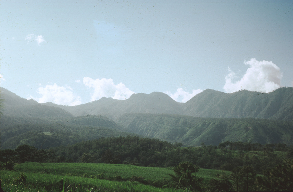 Volcán San Juan, the NW-most major volcano of the Mexican Volcanic Belt, displays an irregular profile west of the city of Tepic.  The northern wall of a 1 x 4 km wide, oval-shaped caldera that was created about 15,000 years ago forms the right-hand horizon.  The rounded notched peak on the center horizon is an intracaldera lava dome that was constructed shortly thereafter.  The flanks of Cerro Alto stratovolcano, the 2240 m high point of the San Juan volcanic complex, can be seen at the extreme left. Photo by Jim Luhr, 1976 (Smithsonian Institution).