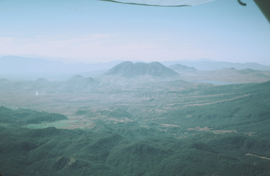 The indistinct elliptical 7 x 10 km wide San Pedro caldera is seen here in an aerial view from the NE, with Laguna San Pedro on the right.  The rim of the caldera is exposed only on the east side (left), where it truncates early Pleistocene andesitic-to-dacitic lava domes.  The caldera partially cuts the 1.1 million-year-old Cerro Grande shield volcano, whose low-angle slopes can be seen beyond the left side of the three coalescing post-caldera Cerro San Pedro lava domes (center). Photo by Jim Luhr, 1979 (Smithsonian Institution).