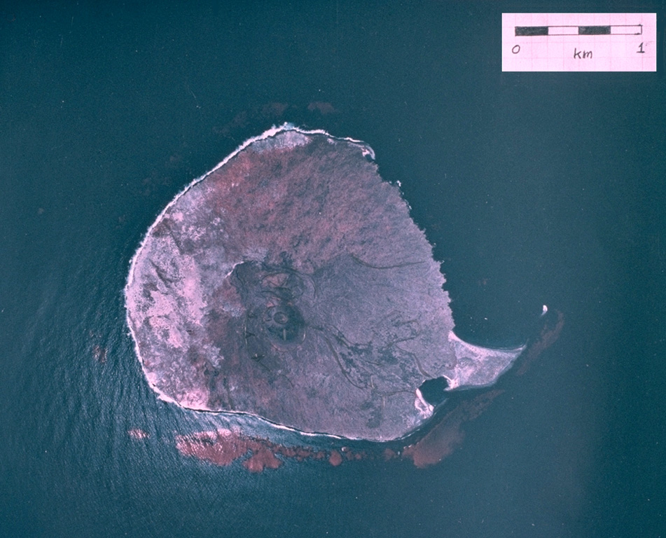 A vertical aerial photograph shows the small, roughly 1-km-wide Isla San Martín, the westernmost of the small volcanoes of the San Quintín volcanic field.  Isla San Martín lies 6 km off the Pacific Ocean coast from the rest of the volcanic field and consists of a small basaltic shield volcano capped by a less than 40-m-high cinder cone.  The peninsula at the SE (lower right) side of the island is formed by a lava flow. Aerial photo by Comisión de Estudios del Territorio Nacional (CETENAL), 1:25,000, 1999.