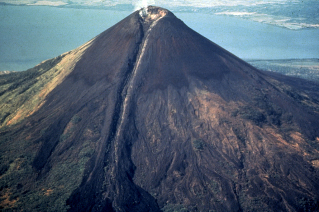 Dramatic levees flank the 1905 lava flow, which originated from the breached summit crater of Momotombo.  The flow was confined in levees on the upper 1000 m of the cone before spreading laterally at the base of the volcano.  Momotombo volcano towers to 1297 m above Lake Managua.  The young cone forming the summit largely fills and overtops a 1.1 x 1.5 km wide crater produced during a major eruption about 2700-2800 years ago. Photo by Jaime Incer, 1991.
