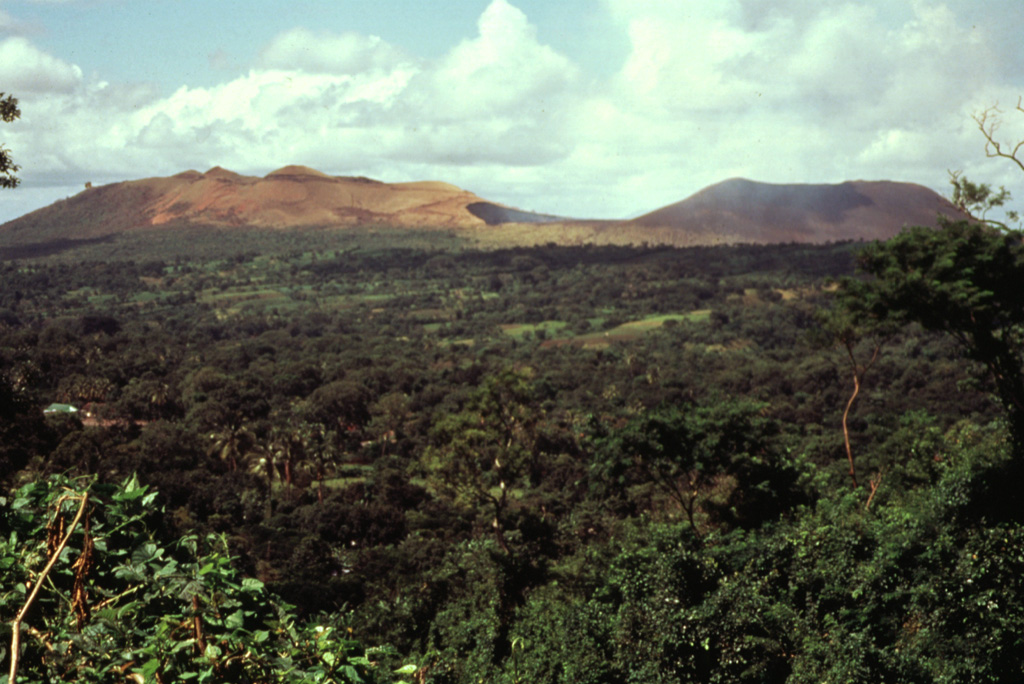 Masaya (left) and Nindirí (right) cones are seen here from the NW across the floor of Masaya caldera.  Santiago crater, the source of most of Masaya's historical eruptions, lies in the saddle between the two cones.  Historical and prehistorical lava flows blanket the caldera floor. Photo by Jaime Incer, 1990.
