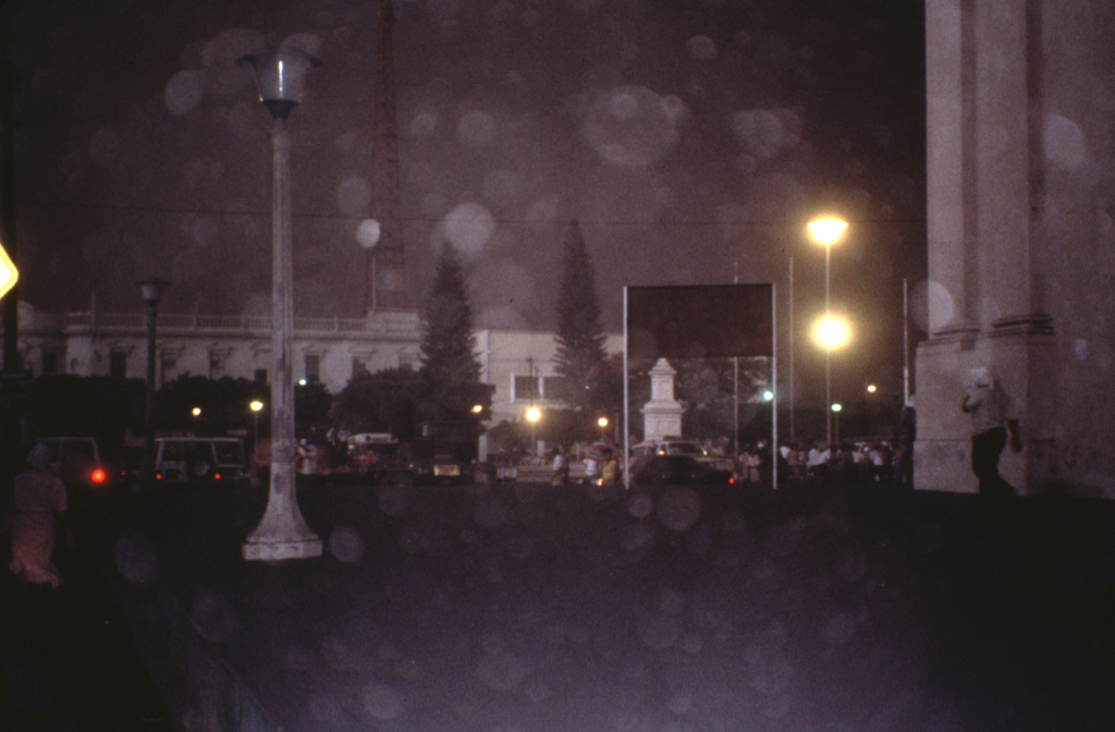Street lights burn during daytime as heavy ashfall turns afternoon into night on the streets of León (18 km WSW of Cerro Negro) during an April 1992 eruption.  Violent strombolian eruptions during 9-14 April produced heavy ashfall, damaging croplands and forcing the evacuation of 28,000 people.  On the evening of 10 April, 15 houses and other structures, including large storage buildings, collapsed in and near León.  Collapses of numerous farm buildings, rural homes, and school buildings were reported over the next several days.  Photo by Jaime Incer, 1992.