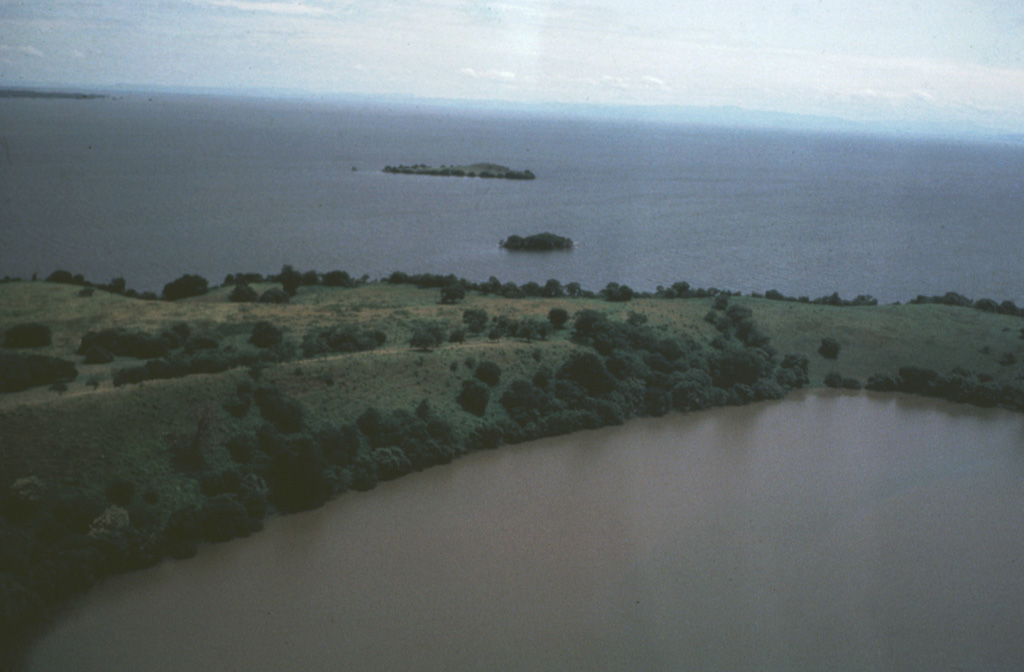 The low-rimmed Zapatera maar in the foreground is part of a maar complex at the NW tip of Zapatera Island on the western side of Lake Nicaragua.  Remnants of other maars form small islets offshore.  The surface of Lake Nicaragua, the country's largest body of water, lies only 30 m above sea level.  The northern shore of the lake in the distance is about 35 km from Isla Zapatera.  The long axis of the 70 x 160 km wide lake parallels the NW-SE trend of the Nicaraguan central depression.  Photo by Jaime Incer, 1982.