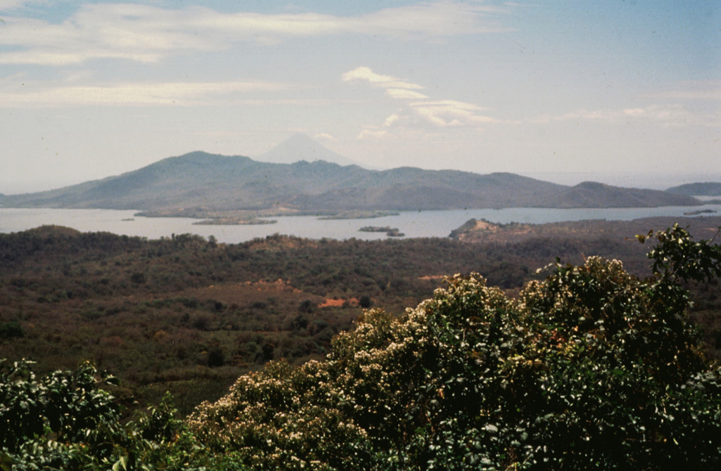 Zapatera Island, seen here from the NW on the lower flanks of Mombacho volcano, is a small low shield volcano that forms a 7 x 10 km wide island in Lake Nicaragua.  The small roughly circular 2-km-wide El Llano caldera is located near the center of the island.  Numerous low-rimmed tuff rings and maars are found on the northern and western sides of the densely forested 629-m-high island and across a narrow strait on the adjacent mainland.  Concepción is the conical volcano in the distance beyond Zapatera. Photo by Jaime Incer, 1995.