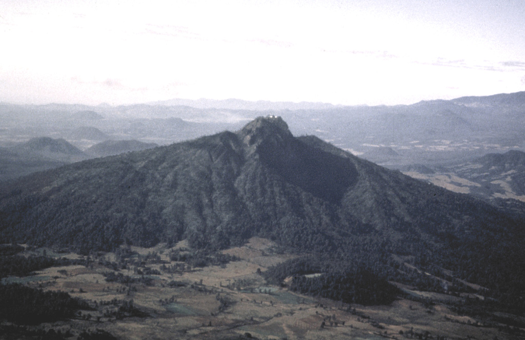 Paracho volcano is one of the many cones of the Michoacán-Guanajuato volcanic field. It is seen here from the west with its summit crater filled by a flat-topped lava dome that is the site of a radio antenna station. The dome fills the upper end of a large erosional valley that extends down the flank from the summit. Edifice collapse has occurred on the eastern side of the volcano, producing a major debris avalanche deposit covering an area of about 175 km2. Photo by Hugo Delgado, 1991 (Universidad Nacional Autónoma de México).