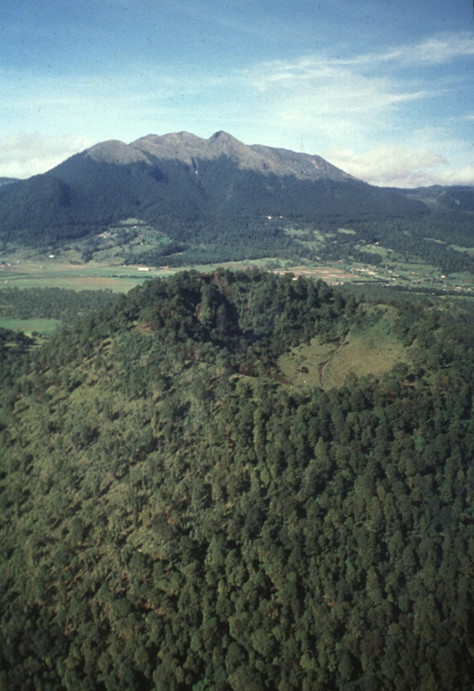 Xitle scoria cone, seen here in an aerial view from the NE with Ajusco volcano in the background, is one of the youngest cones of the Chichinautzin volcanic field. It is about 100 m high, with a crater that is 350 m wide and 115 m deep, and it formed around 2,000 years ago. Xitle (also known as Xicti) means “belly button” in the Nahuatl language, a reference to the shape of the cone and its crater. Volcán Ajusco is a Pliocene-Pleistocene lava dome complex surrounded by block-and-ash flow deposits. Photo by Hugo Delgado, 1995 (Universidad Nacional Autónoma de México).