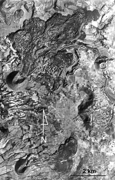 Volcán la Mina is the scoria cone near the center-left margin of the photo with the lava flow emplaced through the collapsed NE crater rim. It formed about 17,170 years ago within the Michoacan-Guanajuato volcanic field, around 90 km ENE of Parícutin. The SW cone containing a crater that also opens to the NE is Volcán el Melón (lower left), which was the source of a lava flow that traveled east to the present-day outskirts of the village of Capula. Aerial photo by Comisión de Estudios del Territorio Nacional (CETENAL).