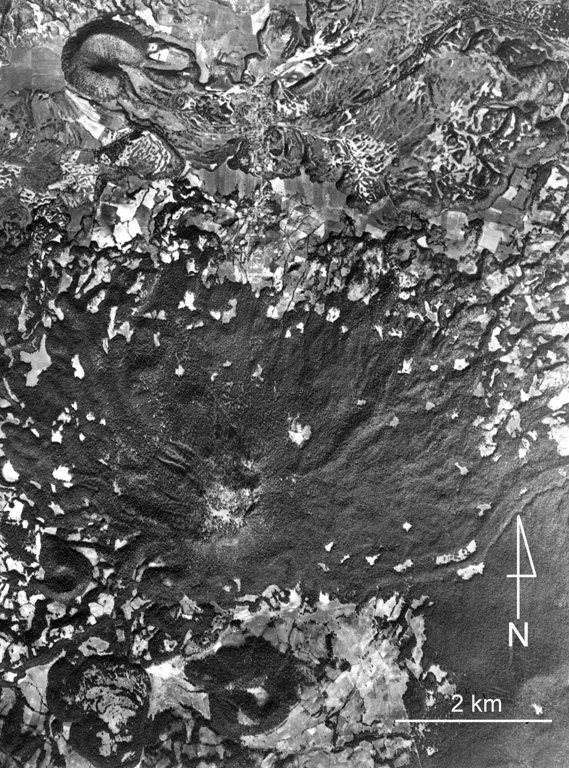 The large forested (dark) area near the center of the photo is Cerro Tecolote, an eroded stratovolcano located roughly 50 km NE of Parícutin within the Michoacan-Guanajuato volcanic field. Cerro las Cabras (upper left) is a scoria cone that produced the lava flow extending across the upper part of the photo. Mexican Highway 15 travels across the flow, which is of Pleistocene age. Cerro Pajarito is one of the scoria cones south of Cerro Tecolote, and another cone is seen here on the SW flank. Aerial photo by Comisión de Estudios del Territorio Nacional (CETENAL).