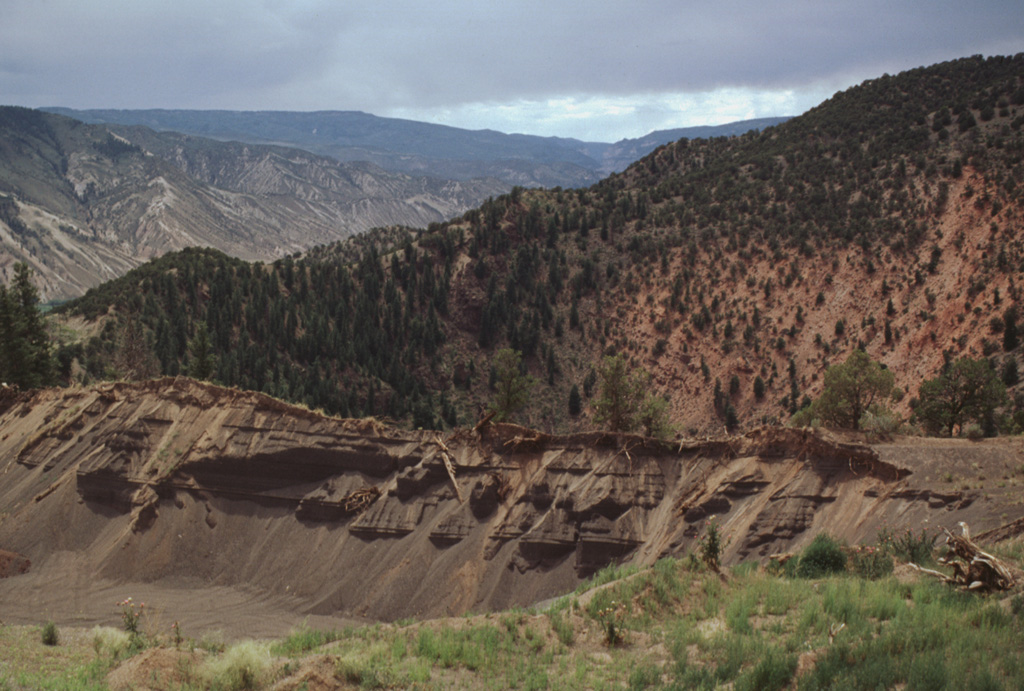During the mid-Holocene a maar was formed in central Colorado near the junction of the Colorado and Eagle Rivers west of the Gore Range.  The quarry in the foreground is cut into basaltic tephra deposits on the rim of the maar.  The 700 m wide maar is 400 m deep and cuts a ridge of evaporites and reddish oxidized sandstones of Pennsylvanian age, which can be seen on the far crater wall.  The maar was erupted about 4150 radiocarbon years ago and is the youngest volcanic feature of Colorado.  The Eagle River lies to the south in the valley beyond the crater. Photo by Lee Siebert, 1999 (Smithsonian Institution).