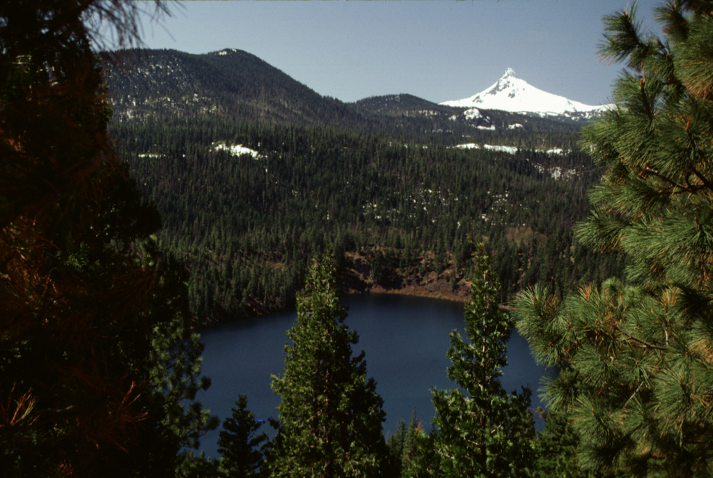 Blue Lake Crater in the foreground is one of three overlapping craters located east of Santiam Pass. The craters formed about 1,300 years ago during explosions through older volcanic bedrock; a chain of spatter cones about 6 km SSW of Blue Lake may have been active during the same eruption. The snow-covered summit of Pleistocene Mount Washington is visible in the background. Photo by Lee Siebert, 1999 (Smithsonian Institution).