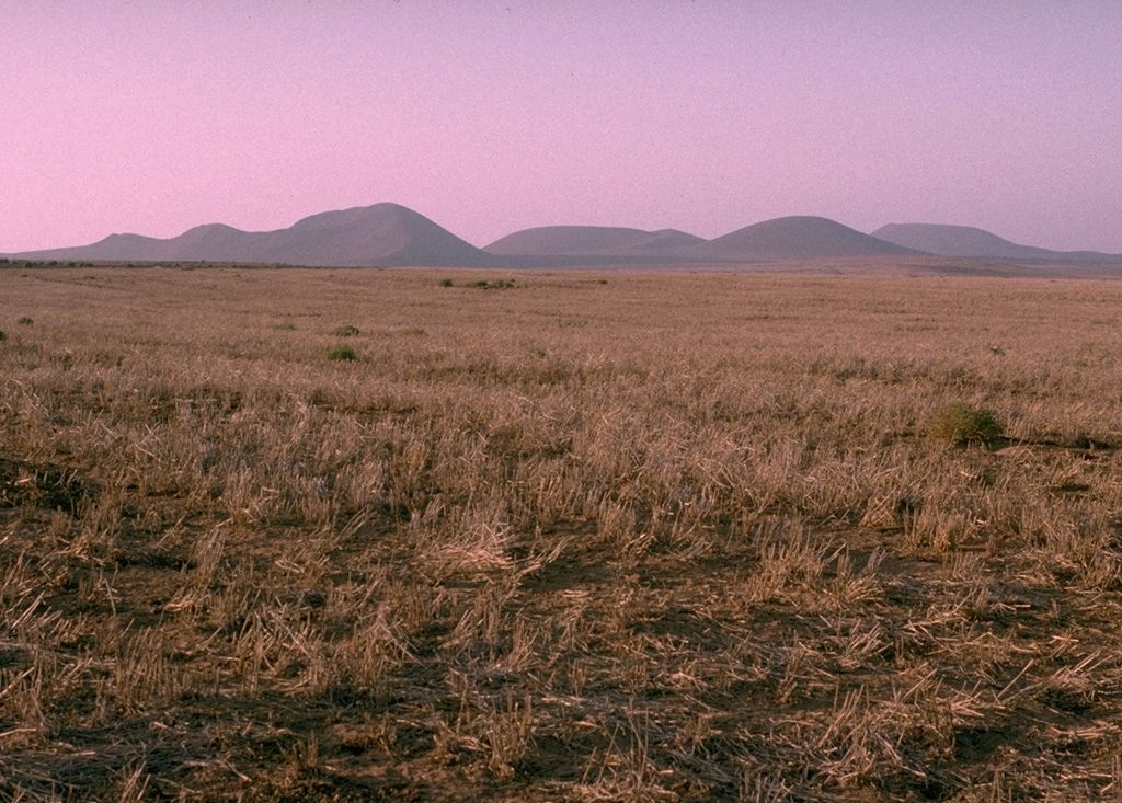 The Woodford group (Ieft) and Media Luna (right), seen here from the SSE, comprise the northern group of cones of the San Quintín Volcanic Field. It consists of a cluster of scoria cones and associated lava flows. The large cone of Media Luna opens towards the east, and it produced a lava flow in that direction. Photo by Jim Luhr, 1990 (Smithsonian Institution).