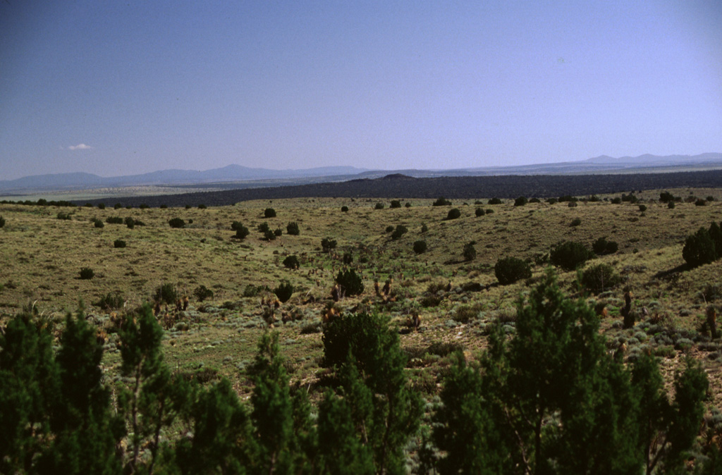 The small dark hill in the middle distance right of center is Little Black Peak, a cinder cone topping a broad low shield volcano that was the source of the massive Carrizozo lava flow, which forms the dark streak extending across the photo.  Most of the ~4.2 cu km pahoehoe flow extended off the photo to the right down the low-angle gradient of the Tularosa Basin to the SE for a distance of 75 km.   Photo by Lee Siebert, 1999 (Smithsonian Institution).