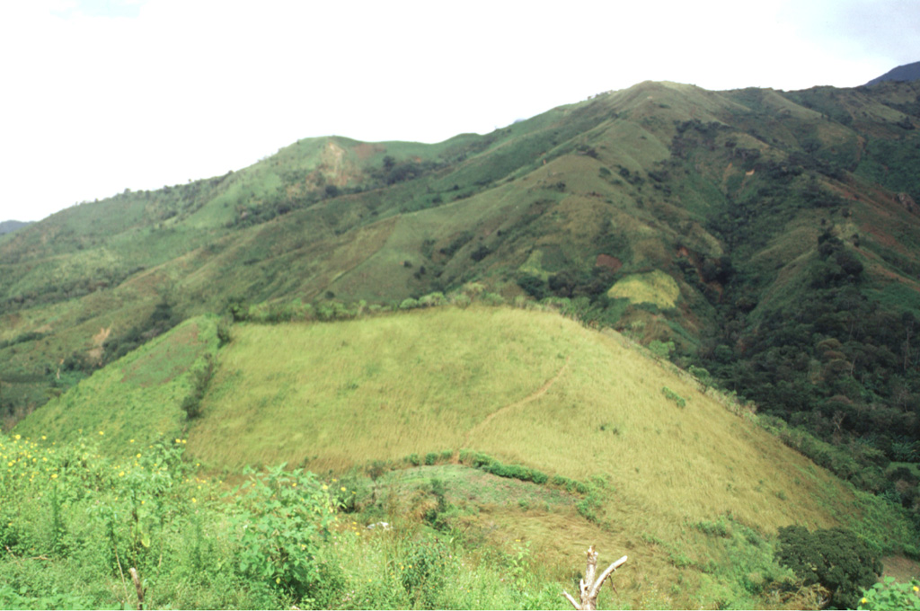 The Media Luna scoria cone in the center of the photo formed in the middle of the Media Luna valley immediately NW of the settlement of the same name. The cone contains two craters and it opens up towards the west. A lava flow from the base of the cone traveled about 3 km down the valley. A radiocarbon date of about 360 years ago was obtained from sediments within a lake formed by the flow.  Photo by Lee Siebert, 1998 (Smithsonian Institution).