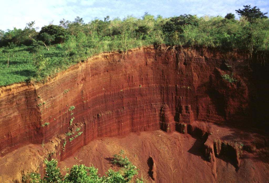 A quarry exposes bedded oxidized scoria layers in a cinder cone of the fissure-fed Granada alignment.  The cone was constructed along a semi-arcuate, N-S-trending fracture located between the city of Granada and the northern flanks of Mombacho volcano, east of the rim of Apoyo caldera.  The lineament is also known as the La Joya alignment, after the explosion craters located SW of Granada.  The alignment originated about 12,000 years ago, and its latest eruptions may have occurred as recently as about 2000 years ago. Photo by Lee Siebert, 1998 (Smithsonian Institution).