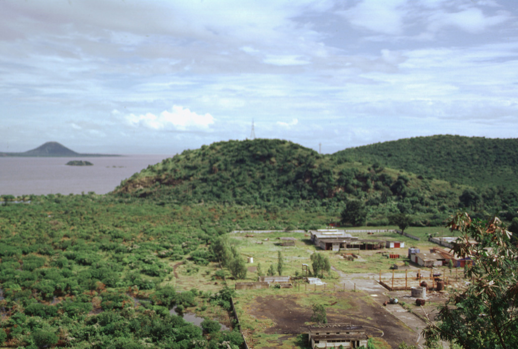 The N-S-trending Nejapa-Miraflores alignment of cones cuts across the western outskirts of the city of Managua and extends across a bay of Lake Managua onto the Chiltepe Peninsula.  Cerro San Carlos (center) lies along the southern side of the bay, while the conical peak of Volcán Chiltepe is visible at the upper left on the eastern tip of the Chiltepe Peninsula. Photo by Paul Kimberly, 1998 (Smithsonian Institution).