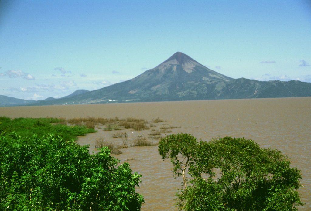 Conical Momotombo volcano rises above the shores of Lake Managua, its waters dirtied by floods associated with hurricane Mitch in 1998.  Momotombo rises about 1250 m above the surface of the lake, which is only about 40 m above sea level.  The dramatic volcano is one of Nicaragua's most prominent landmarks and is featured on many of the country's postage stamps. Photo by Lee Siebert, 1998 (Smithsonian Institution).