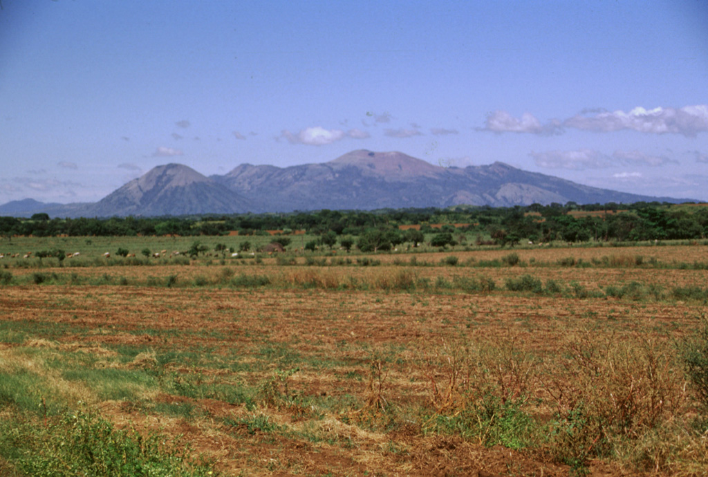 Las Pilas volcanic complex forms a broad massif seen here from the SSE rising above the Nicaraguan depression.  This 30-km-long chain was erupted along a N-S-trending fissure and includes (from left to right) conical Asososca volcano, flat-topped Cerro Los Tacanistes, the unforested summit of Las Pilas itself (the high point of the range), and Cerro El Picacho. Photo by Lee Siebert, 1998 (Smithsonian Institution).