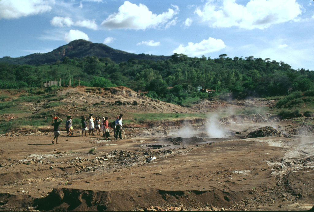 Forested Rota volcano rises above steaming ground of the San Jacinto thermal area at the eastern end of the Telica volcanic complex.  Highway 26 between Telica and Malpaisillo crosses the low saddle between Rota and the Telica complex and provides easy access to the mud pots and steaming vents of the thermal area.  Visitors to San Jacinto are accompanied by groups of vendors who live in settlements near the thermal area.  Photo by Lee Siebert, 1998 (Smithsonian Institution).