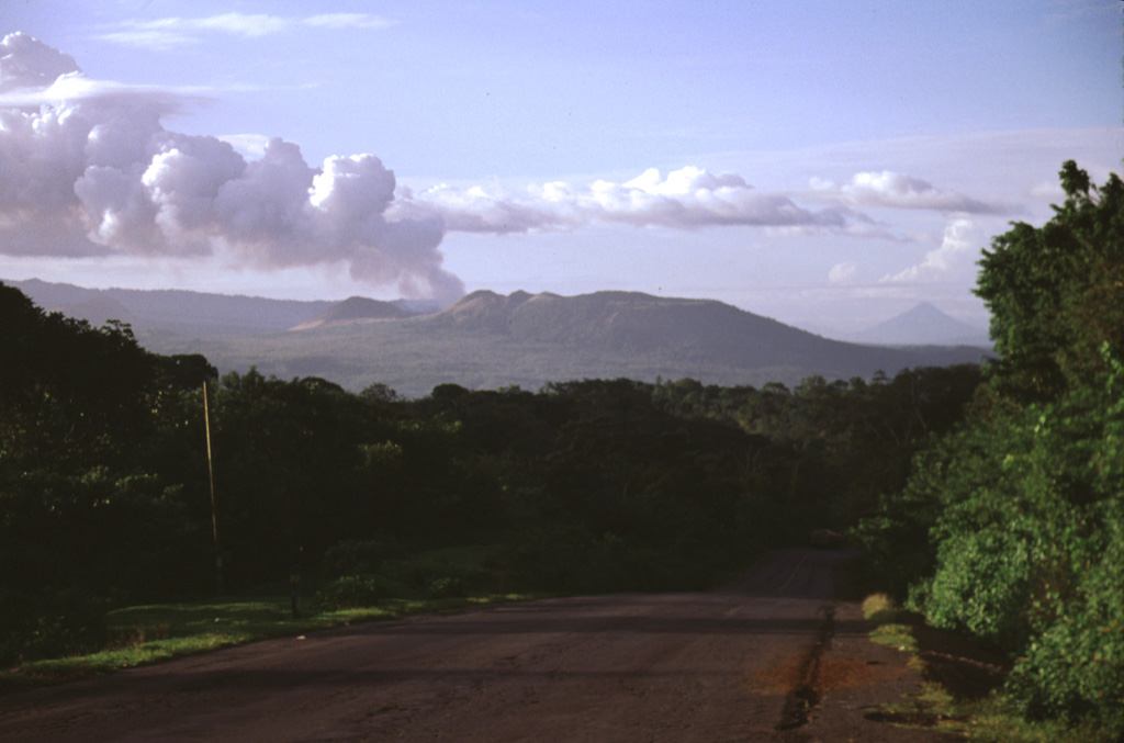 A vigorous gas plume is seen exiting from Masaya volcano in November 1998.  Masaya's latest episode of degassing activity began in mid 1993.  Prevailing winds typically distribute plumes from Masaya to the west, where they come in contact with the higher-elevation Las Sierras highlands (left horizon).  The volcanic emissions during 1998-1999 affected a 1250 km2 area downwind, causing health hazards and extensive vegetation damage, resulting in economic losses to coffee plantations.  Photo by Lee Siebert, 1998 (Smithsonian Institution).