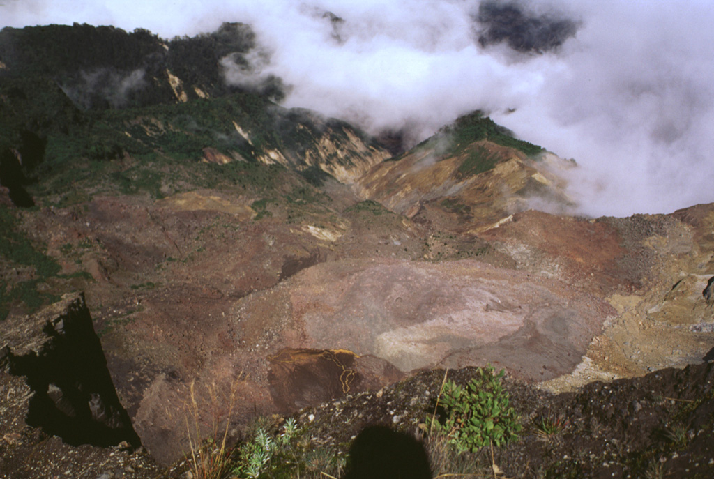 This area was impacted by an 8 December 1994 phreatic explosion is visible from the NW rim of Irazú's summit crater, seen here in 1998. The explosion originated from a geothermal area (lower right) on the upper NW flank and destroyed vegetation down to 2,500 m elevation. The explosion, which produced no juvenile material, created an irregular crater 60-80 m in diameter and sent ashfall to about 30 km distance. Landslides and lahars traveled down the Río Sucio drainage (right center). Photo by Lee Siebert, 1998 (Smithsonian Institution).