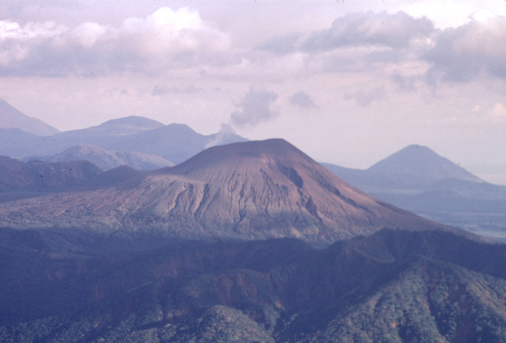 Telica volcano is seen here in a telephoto view looking down the Marrabios Range from near the summit of Casita volcano.   A thin steam plume rises from a fumarole in the summit crater.  Behind Telica on the left horizon is Las Pilas volcano, and the conical peak at the extreme right is Cerro Asososca, at the south end of the Las Pilas complex. Photo by Paul Kimberly, 1998 (Smithsonian Institution).
