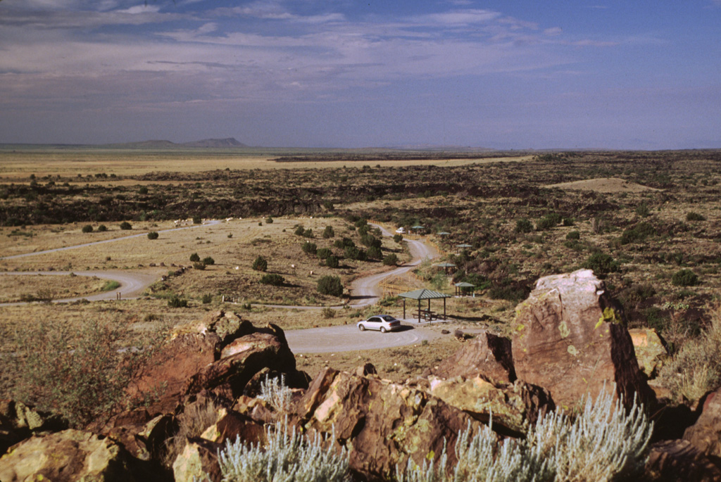 The Carrizozo lava flow surrounds the southern end of a kipuka providing a campground site in the Valley of Fires Recreation Area.  This massive tube-fed pahoehoe lava flow, with a volume of about 4.3 cubic km, traveled 75 km down the extremely low-angle floor of the Tularosa Basin, with slopes of less than half a degree.  The flow was inferred to have been emplaced during low-effusion-rate, long-duration eruption lasting 2-3 decades. Photo by Lee Siebert, 1999 (Smithsonian Institution).