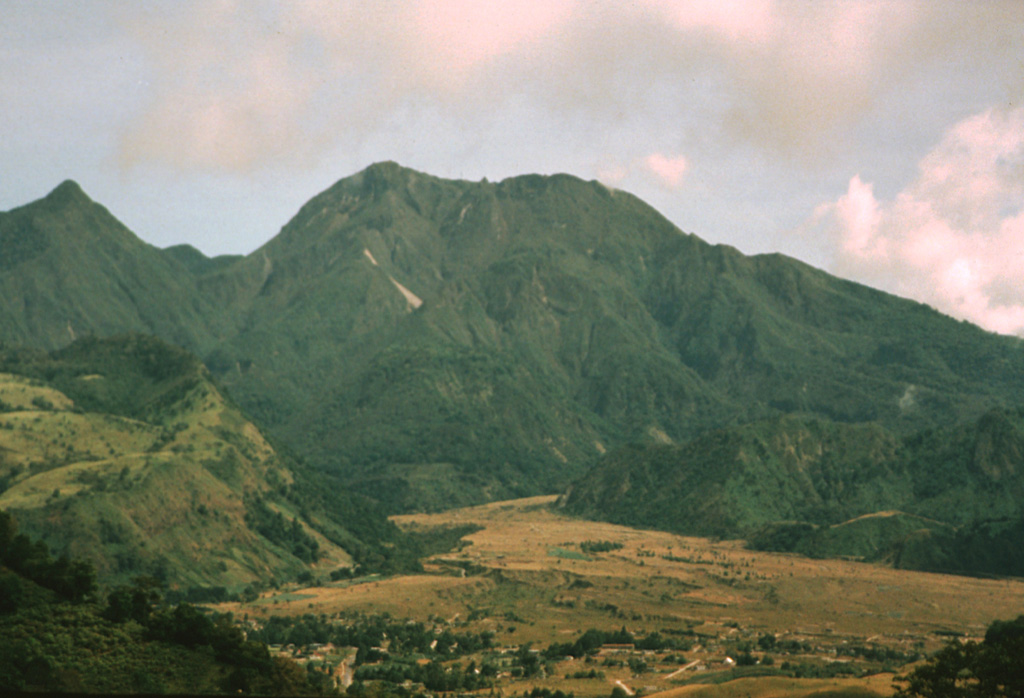 The 10-km-long northern wall of Volcán Barú's horseshoe-shaped collapse scarp extends from the grassy ridge at the lower left to the peak to the upper left. In the center is the large lava dome complex that has filled much of the scar. The light-colored valley floor of Río Macho de Monte in the foreground is composed of pyroclastic flow deposits related to growth and collapse of the summit lava domes. The town of Nuevo Bambito is visible at the bottom of the photo. Photo by Kathleen Johnson, 1995 (University of New Orleans).