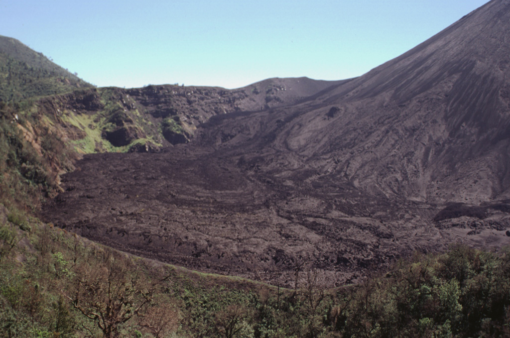 Lava flows erupted in September 1998 cover the floor of the caldera moat of Pacaya. The caldera wall here is about 100 m high. Frequent lava flows from MacKenney cone, whose flank is to the right, have been gradually forming deposits to tens of meters higher than it was a decade ago. Eruptions at MacKenney cone have been frequent since its initial eruption in 1965. The ridge in the foreground is the crater rim of Cerro Chino. Photo by Paul Kimberly, 1999 (Smithsonian Institution).