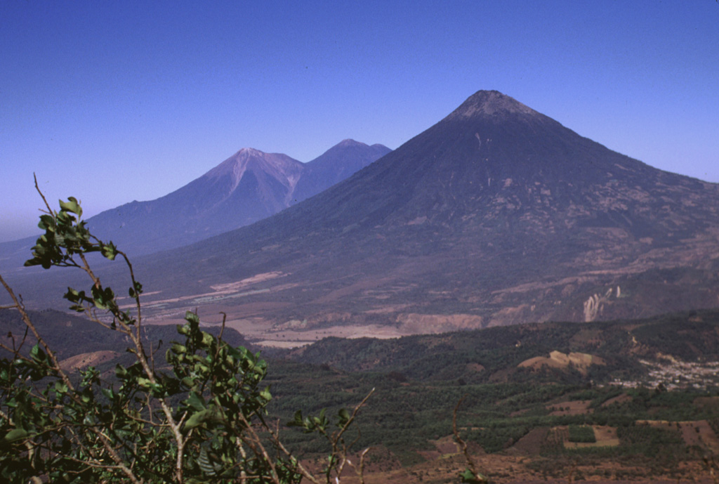This view from Pacaya shows Fuego and Acatenango (left) and conical Volcán de Agua volcano (right). These impressive volcanoes all exceed 3.5 km in elevation and rise from near sea level on the Pacific coastal plain to the south. Volcanism at the Acatenango-Fuego pair has migrated southwards, and Fuego, its summit kept free of vegetation by frequent eruptions, is one of Guatemala's most active volcanoes. Photo by Lee Siebert, 1999 (Smithsonian Institution).
