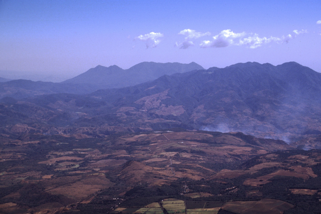 The deeply eroded Plio-Pleistocene stratovolcano at the upper right is Pueblo Nuevo Viñas (also known as Cerro la Gabia). Four scoria cones are located on the NE flank, and lava flows from the volcano cover the western portion of the Cuilapa quadrangle. This view is from the NW at the summit of Pacaya volcano with Tecuamburro volcano on the center horizon. Flank activity from Tecuamburro has occurred as recently as about 3,000 years ago. Photo by Lee Siebert, 1999 (Smithsonian Institution).